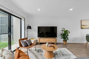 a living room with a couch and a tv at Steps to the Beach Cafes moderm stylish 3BR in Christies Beach