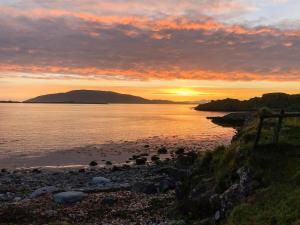 a sunset on the shore of a body of water at Aird House in Ardfern