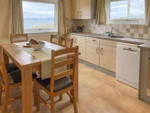 a kitchen with a wooden table with chairs and a sink at Aird House in Ardfern