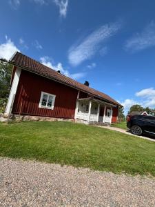 a red house with a car parked in front of it at Torpidyll nära sjö in Vetlanda