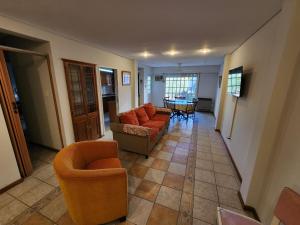 a living room with orange chairs and a table at Departamento Microcentro San Rafael in San Rafael