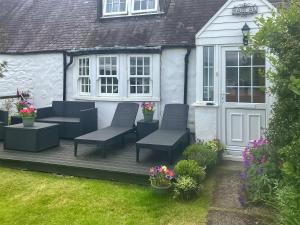 a patio with two chairs and a table and some flowers at Raglan Cottage in Ardentinny