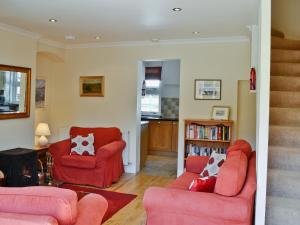 a living room with two red chairs and a book shelf at Dunardry View in Lochgilphead