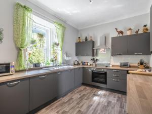 a kitchen with grey cabinets and green curtains at Pier Haven - Cottage in Blairmore