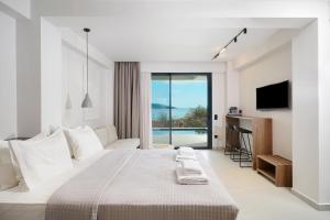 a white bedroom with a large bed and a television at Ethos Zeen Private Pool Suites in Potamiá +138 photos