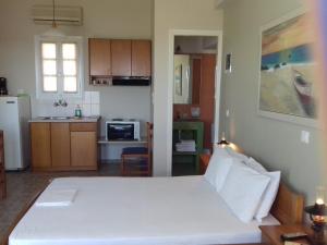 a bedroom with a large white bed and a kitchen at Kyklades in Agios Ioannis