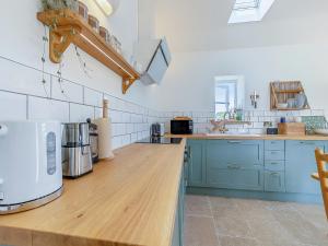 a kitchen with blue cabinets and a wooden counter top at Dunnock - Uk50146 in Faversham
