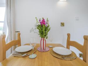 a dining room table with two plates and a vase of flowers at Linnet - Uk50154 in Faversham +19 photos