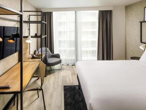 a hotel room with a bed and a desk at ibis London Sutton Point in Sutton