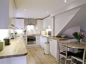 a kitchen with white cabinets and a table with chairs at Blackmill Cottage in Taynuilt