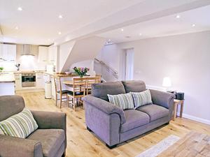 a living room with two couches and a kitchen at Blackmill Cottage in Taynuilt