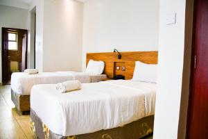 a hotel room with two beds with white sheets at Decale Jewel Stone Hotel in Nairobi +64 photos