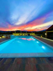 a large blue swimming pool with a sunset in the background at Cosy Cottage with Private Pool - Andrej in Danilovgrad