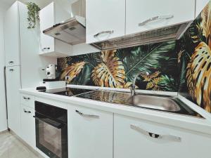 a kitchen with a sink and a tropical wallpaper at Abbate Apartments MIRI in Palermo