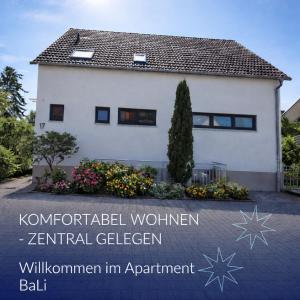 a white house with a sign in front of it at Apartment_BaLi in Linkenheim-Hochstetten