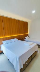 a bedroom with a large white bed with a wooden headboard at Residencial Ibiapaba FLAT 31 - com piscina e ótima localização in Camocim