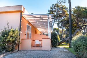 a house with a porch with a white chair on a patio at Tuscany Hotel Alle Dune in Marina di Castagneto Carducci