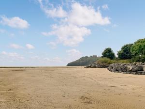 an empty beach with rocks and a blue sky at Beachside in Llanstephan