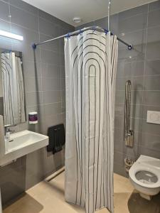 a bathroom with a shower curtain next to a toilet at Green Marmot Capsule Hotel Genève - Self check-in in Geneva