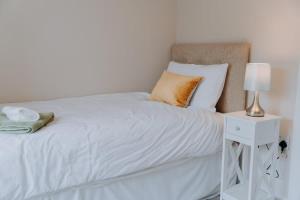 a white bed with a lamp on a side table at Charming St Davids Cottage with Cathedral Views in St. Davids