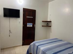 a room with a bed and a door with a television at Hotel Maria in Marabá
