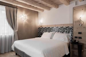 a bedroom with a large white bed and a window at Hotel Orso Grigio in Cavalese