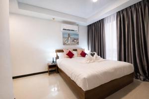 a bedroom with a large white bed with red pillows at KAI Condo 1BR Pool View NBC Nai Harn in Rawai Beach