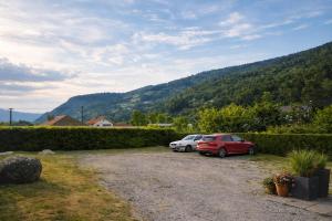 two cars parked in a gravel parking lot with mountains in the background at Le Petit Loft Vosgien -Escapade nature & cosy in Cornimont