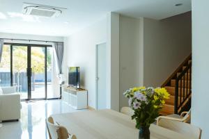 a dining room with a table with a vase of flowers on it at Chaba Pool Villa Khao Lak in Khao Lak