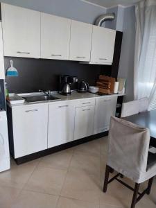 a kitchen with white cabinets and a chair and a sink at Апартамент Лана 2 in Byala