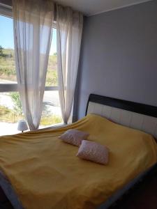 a bedroom with a bed with two pillows and a window at Апартамент Лана 2 in Byala