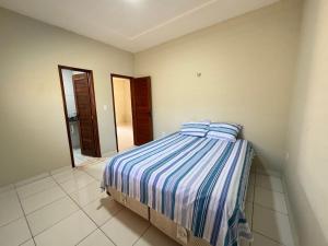 a bedroom with a bed with a striped comforter and a mirror at Casa em Tibau in Tibau
