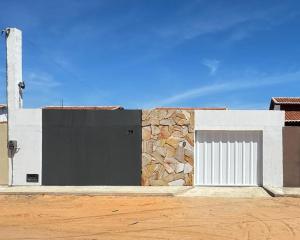 a building with a black door and a stone wall at Casa em Tibau in Tibau