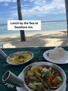 ein Tisch mit zwei Tellern Essen am Strand in der Unterkunft Seashore Inn in Siquijor