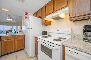 a kitchen with white appliances and wooden cabinets at Driftwood Towers 5E in Gulf Shores +25 photos
