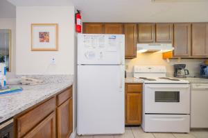 a white refrigerator in a kitchen with wooden cabinets at Driftwood Towers 5E in Gulf Shores