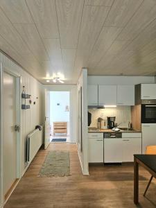 a kitchen with white cabinets and a table in it at Drømmehus Ferienwohnungen in Nørre Nebel