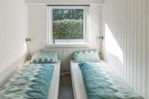 two beds sitting in a room with a window at Drømmehus Ferienwohnungen in Nørre Nebel