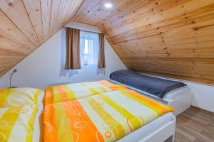 a bed in a small room with a wooden ceiling at Vilka Cibulka a chata Cesnačik in Ižipovce