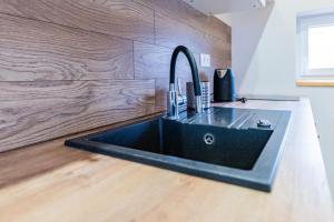 a black sink in a kitchen with a wooden wall at Vilka Cibulka a chata Cesnačik in Ižipovce +55 photos