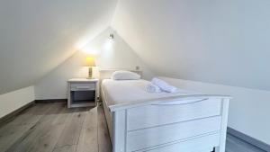 a small attic bedroom with a bed and a lamp at Le Nid Des Grands Geais in Le Crotoy