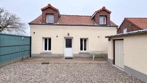 a white house with a bench in front of it at Le Nid Des Grands Geais in Le Crotoy