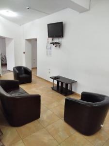 a room with two chairs and a table and a tv at Perla Sarisorului in Sărişor