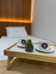 a tray with two coffee cups and a plant on it at Residencial Ibiapaba Flat 16 - Com piscina e ótima localização in Camocim