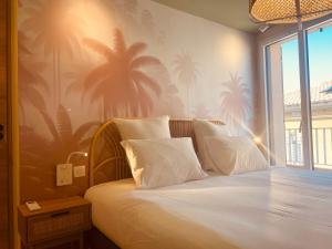 a bedroom with a bed with palm trees on the wall at La Maison Cavet 6 Appartements de standing au cœur du village in Sanary-sur-Mer