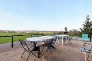 two tables and chairs on a patio with a view at La Clairière de Dogneville - proche Epinal in Dogneville