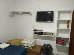 a room with a tv hanging on the wall at Cantinho da Lu em apt inteiro 1km da praia in Bertioga