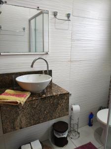 a bathroom with a sink and a mirror and a toilet at Cantinho da Lu em apt inteiro 1km da praia in Bertioga +18 photos