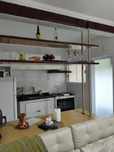 a living room with a white couch and a kitchen at Cantinho da Lu em apt inteiro 1km da praia in Bertioga