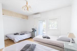 a white room with two beds and a chandelier at Le cocon de Boutiny - à Peymeinade in Peymeinade